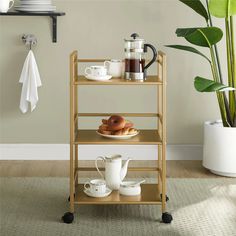 a shelf with coffee and tea on it next to a potted plant in a living room