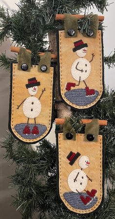 three christmas stockings hanging from a tree with snowmen on them