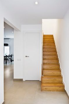 there is a white door and some stairs in this house with light wood flooring