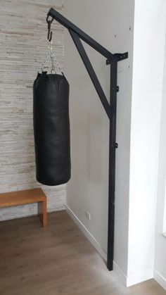 a black punching bag hanging from the side of a white wall next to a bench