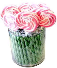 candy canes in a glass jar filled with green and pink lollipops