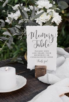 a sign that says memory table next to a candle and some flowers on a table