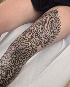 a person laying on a bed with a tattoo on their arm and leg that has an intricate design