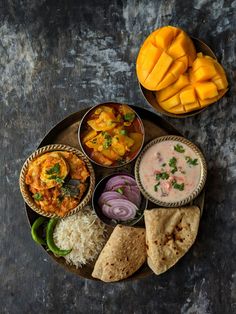 an assortment of food on a plate with rice and mangos next to each other