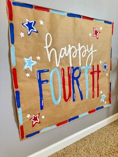 a fourth of july banner hanging on the wall in a room with carpeted flooring