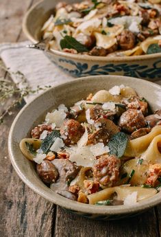 two bowls filled with pasta and meat on top of a wooden table next to each other