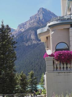 a building with flowers on the balcony and mountains in the backgrouds behind it