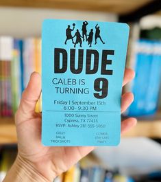 a person holding up a blue card with the words dude is turning 9