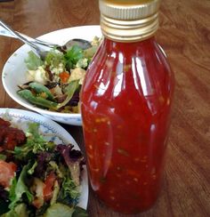 a bottle of ketchup sitting on top of a table next to two plates of food