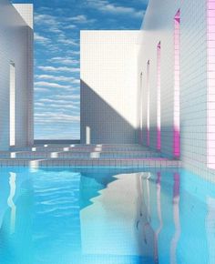 an empty swimming pool surrounded by white brick walls and blue sky with wispy clouds