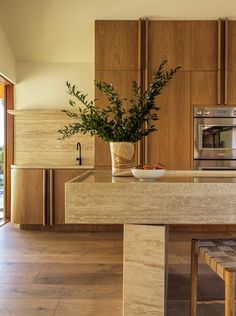 a modern kitchen with wooden cabinets and an island in the middle, along with a potted plant