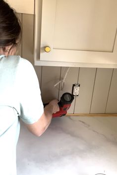 a woman is fixing a cabinet in the kitchen