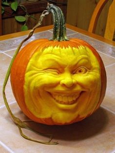 a pumpkin carved to look like an evil man with his mouth open and tongue out