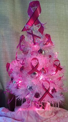 a pink christmas tree decorated with ribbons and ornaments