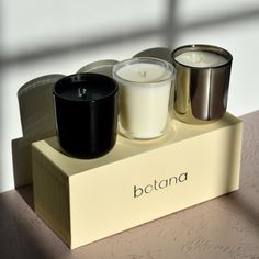 three candles sitting on top of a box with the word botana written in it