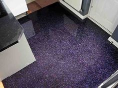 the kitchen floor is shiny purple and has black counter tops with white cupboards on each side