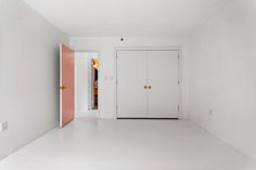 an empty white room with two doors and pink door knobs on the left side