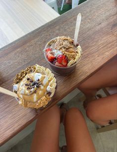 two desserts sitting on top of a wooden table with strawberries and ice cream