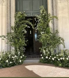 an entrance to a building with white flowers and greenery