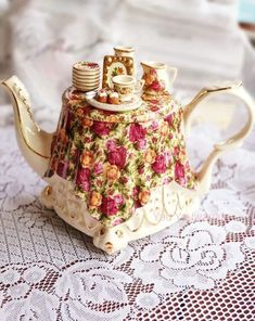 a tea pot with some cookies on it sitting on a lace doily tablecloth