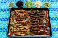 a tray filled with meat and veggies on top of a blue table cloth