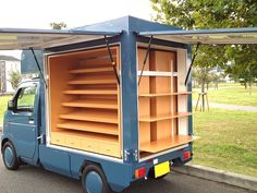 a small blue truck with shelves on the back