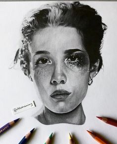 a pencil drawing of a woman's face with her eyes closed and crayons surrounding it