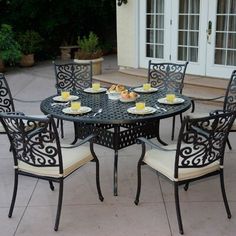 an outdoor table with chairs around it and plates of food sitting on the table outside