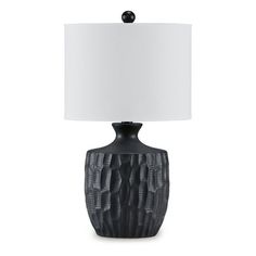 a black table lamp with a white shade on it's base and an intricate design