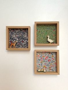 three small wooden boxes with animals and flowers in them on the side of a wall