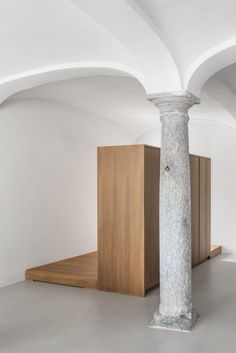 an empty room with white walls and columns in the center, surrounded by wooden boxes