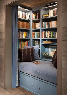 a window seat in the corner of a room with bookshelves and shelves full of books