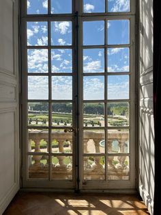 an open door leading to a balcony with a view of the sky and trees outside