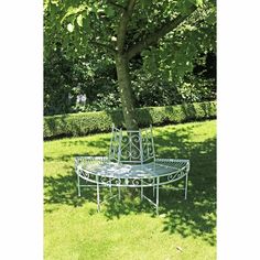 a metal bench sitting under a tree in the grass