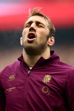 a man with his mouth open wearing a maroon jacket and gold lettering on the chest