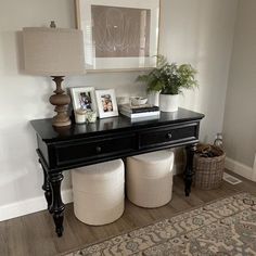 a black table with two white stools under a framed photo and a plant on top