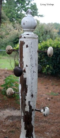 an old wooden pole with knobs and balls on it's side in front of some trees