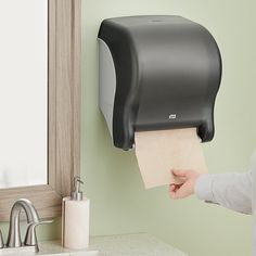 a person holding a piece of paper in front of a toilet paper dispenser