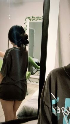 a woman standing in front of a mirror next to a man with his back turned