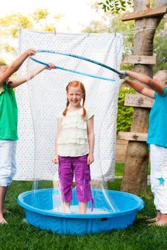 two girls are playing with bubbles in the yard and one girl is jumping on a trampoline