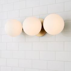 three light fixtures mounted on a white brick wall