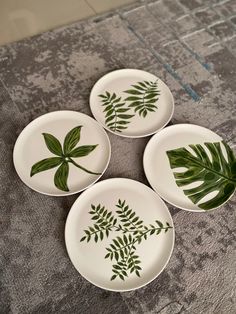 four white plates with green leaves on them