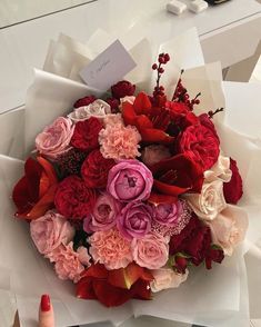 a bouquet of flowers sitting on top of a white paper bag next to a manicure