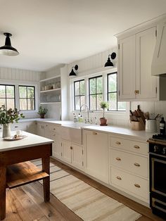 a kitchen with white cabinets and wooden floors, an island in the middle has potted plants on it