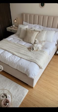 a white bed sitting on top of a hard wood floor next to a wooden dresser