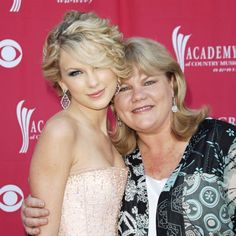 two women hugging each other on the red carpet in front of a wall with an american country music awards logo