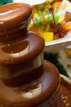 there is a chocolate fountain with fruit in the background