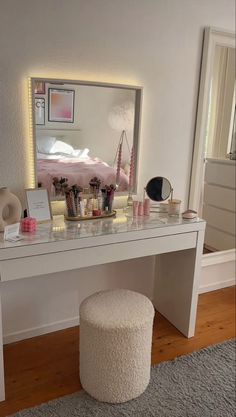 a white vanity table with a mirror and stool