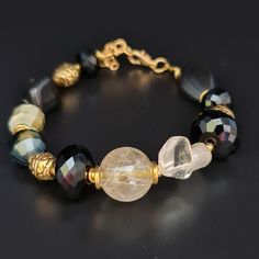 Handmade multistone bracelet of beautiful Rutilated quartz, Golden Tiger's eye, Citrine, Black Agate and faceted Black Glass beads. The bracelet comes in a gift box ready for gifting. You might also like earrings  https://www.etsy.com/uk/shop/LoveIuliia?ref=l2-about-shopname§ion_id=38529364 Not exactly what you are looking for? More of bracelets available here https://www.etsy.com/uk/shop/LoveIuliia?ref=l2-about-shopname§ion_id=38541683 Thank you so much for visiting my shop Iuliia xx Agate Bracelet With Faceted Beads, Spiritual Bracelet With Faceted Beads, Adjustable Faceted Agate Jewelry, Artisan Black Bangle Jewelry, Artisan Bracelet With Faceted Beads, Artisan Faceted Bead Bracelet Jewelry, Artisan Faceted Bead Bracelet, Unique Faceted Round Beads Jewelry, Golden Tiger