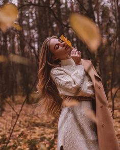 a woman is standing in the woods with her hands on her face and looking up